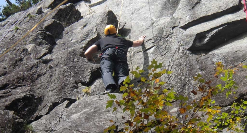 A person wearing a helmet is attached to ropes as they climb a rock face. 